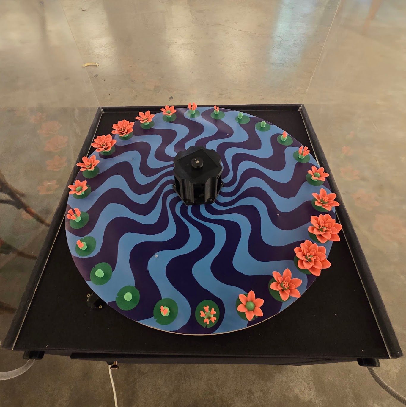 The flower layer seen from directly above — 24 lotus forms around the rim of the painted platter, each one a further stage of opening than the last, from a closed bud to a full bloom
